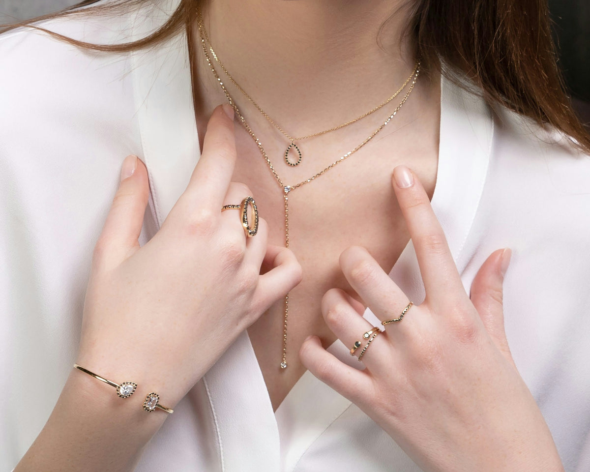 Mujer con camisa blanca luciendo collares, anillos y pulsera dorados minimalistas